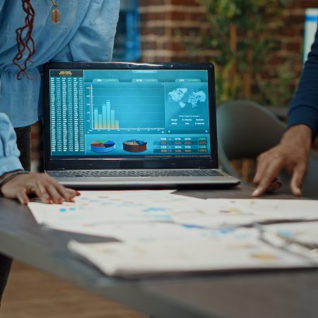 Coworkers examining reports on papers, looking at statistics and annual data analytics to increase profit. Workers group planning research strategy with documents for business development.